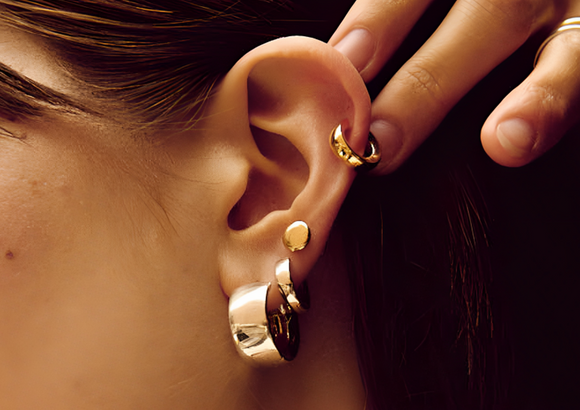 Stacked gold hoop and stud earrings on a female model