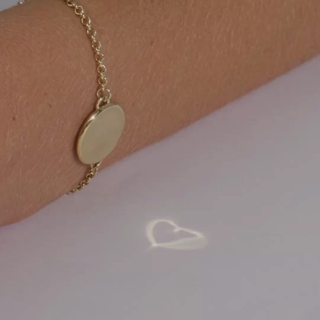 close up of heart caustic bracelet on wrist, reflecting a heart onto the surface