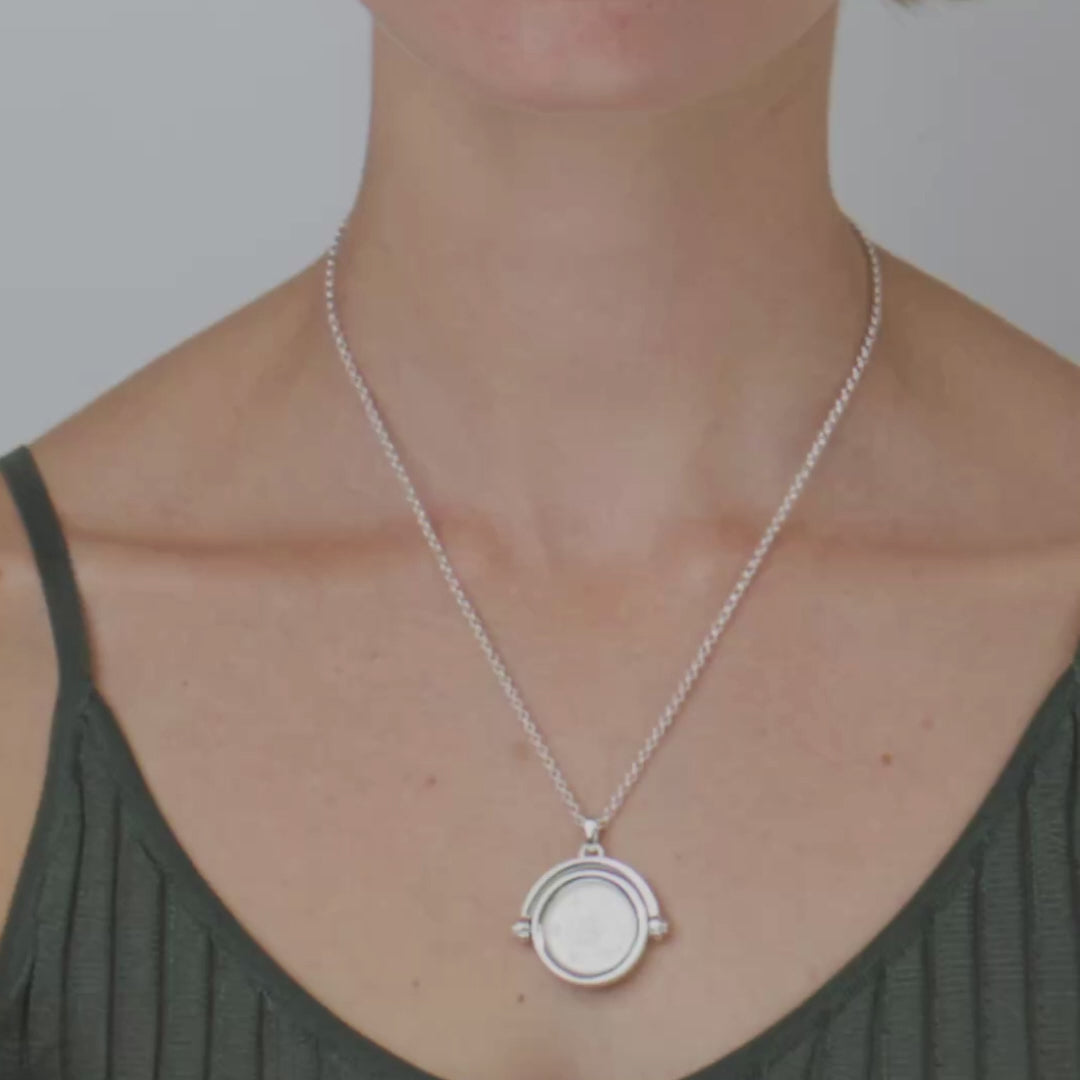 Close up of woman wearing a silver sixpence pendant
